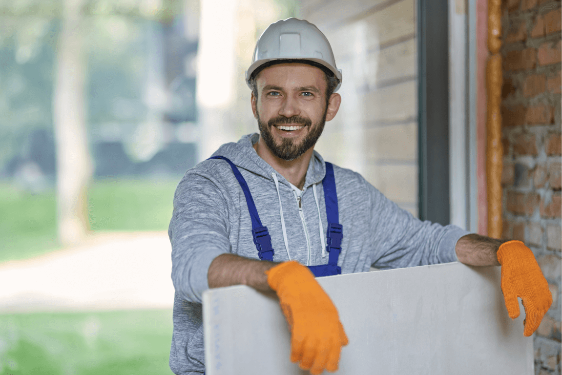 Man leaning on a drywall plank about to take it to be assembled
